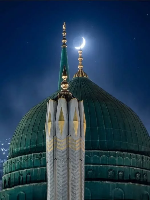 The green dome and minaret at night with a crescent moon